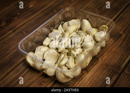 Libre de variété blanche gousses d'ail (Allium sativum), plants préparés pour les semis d'automne, de l'ail dans un bac en plastique sur fond de bois. Banque D'Images