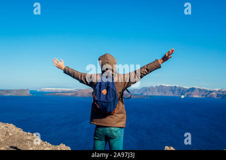 Meilleur homme bras levés se sentir libre et heureux sur l'île de Santorin en automne. Admirant le paysage touristique sur la Caldera Banque D'Images