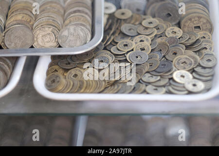 Plateaux avec de vieilles pièces dans la fenêtre d'une boutique d'antiquités. Le Vietnam. Banque D'Images