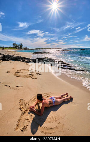 Une femme font figures dans le sable sur la plage de Makalawena, Hawaii Banque D'Images