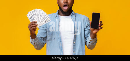 Portrait of African man holding Smartphone avec écran noir et tas d'argent, panorama avec l'espace vide Banque D'Images