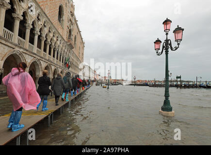 Beaucoup de gens sur la passerelle avec soufflets à Venise en Italie lors de l'inondation près de Palais Ducal et d'une lampe de rue Banque D'Images