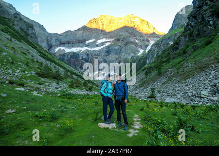 Un couple debout sur une prairie avec vue sur les Alpes, partiellement Schladming encore couvert de neige. Le plus haut atteint lentement printemps parties de la pe Banque D'Images