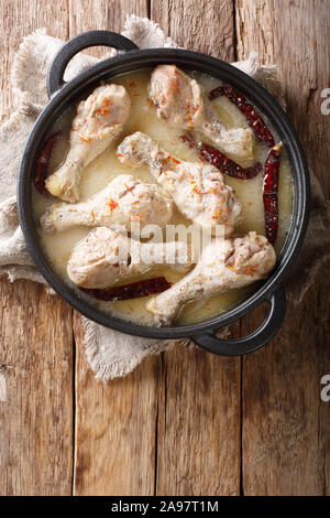 Poulet épicé cuit en fête Rezala sauce yogourt close-up dans une casserole sur la table. Haut Vertical Vue de dessus Banque D'Images