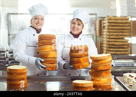 Les pâtissiers gâteaux pour tenir dans leurs mains le gâteau en confiserie . Banque D'Images