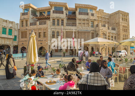 Les femmes et les hommes en Qatari Souk Waqif marche dans la rue et assis dans un restaurant à la lumière du jour Banque D'Images