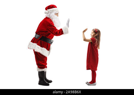 Profil de pleine longueur tourné du Père Noël gesticulant des cinq avec une petite fille isolée sur fond blanc Banque D'Images