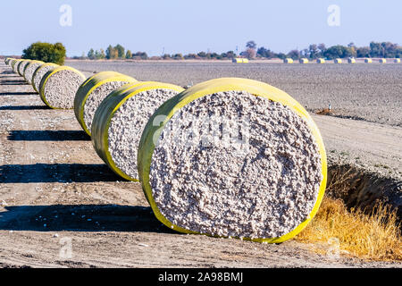 Les balles de coton disposées dans une rangée à côté d'un champ moissonné, prêt pour enlèvement ; Central California, United States Banque D'Images