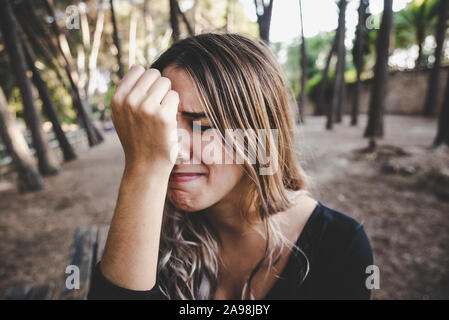 Beau visage de femme sanglotant dans le dégoût qu'elle repose sa tête sur sa main. Banque D'Images