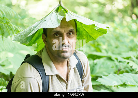 Un homme a mis une feuille verte sur sa tête dans la nature Banque D'Images