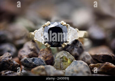 Black diamond magnifique bague avec diamants blancs de chaque côté, dans une bande d'or jaune, reposant sur des pierres précieuses non coupée Banque D'Images