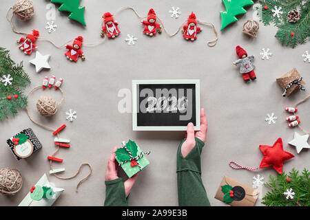 Décor à la main créative, zéro déchets cadre de Noël pour la nouvelle année. Mise à plat, vue du dessus sur du papier craft. Babioles textiles, cadeau en main. Eco friendly Xmas Banque D'Images