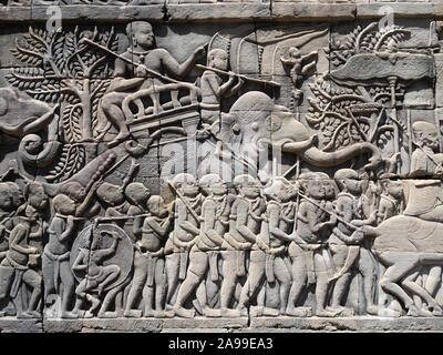 Près d'un bas-relief sculpté avec des guerriers et un éléphant sur le mur de temple Bayon à Angkor Thom à Siem Reap au Cambodge. Banque D'Images