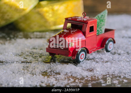 Voiture rouge portant un sapin de Noël sur la neige fond pour célébré Joyeux Noël. Banque D'Images