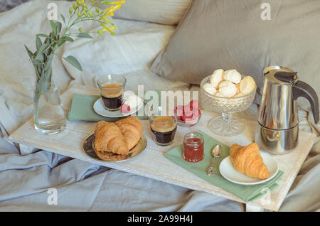 Paysages bonjour , petit déjeuner au lit : cafetière, deux verre de café, croissants, confiture, framboise et fleurs de meringue sur bois bac. Banque D'Images