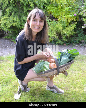 Dame avec un trug plein de légumes dans un jardin Banque D'Images