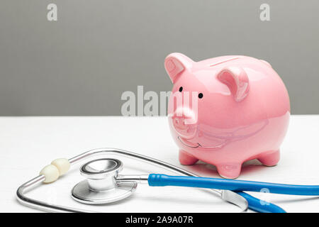 Pink piggy bank et stéthoscope sur un fond gris. Concept de comment économiser sur l'assurance maladie ou une assurance personnelle. Banque D'Images