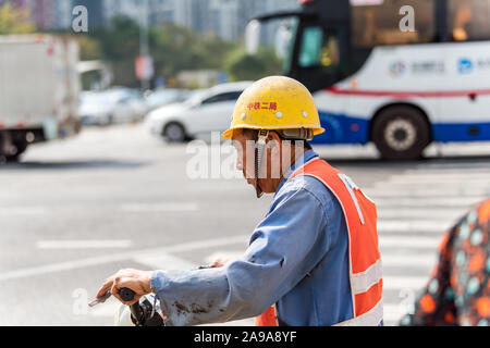 Un travailleur de la construction le port de casque de sécurité au volant d'un scooter à la rue de Shenzhen, Chine. Banque D'Images
