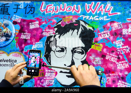 Homme prenant une photo sur mobile à John Lennon Wall Prague Street art graffiti Banque D'Images