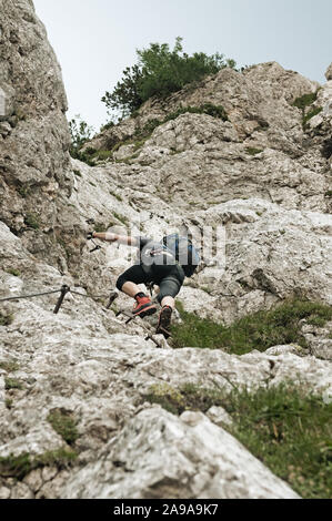Homme d'alpiniste en paroi verticale escalade la via ferrata dans les Alpes juliennes. L'alpinisme, l'escalade et des concepts de protection Banque D'Images
