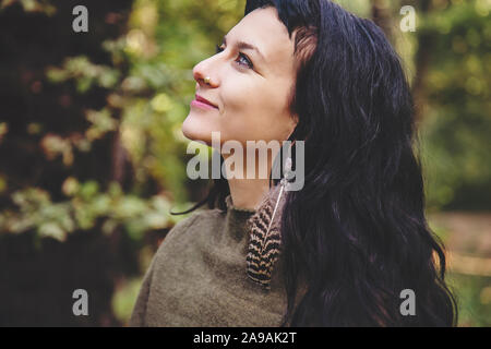 Portrait de belle jeune femme avec feather earring in forest Banque D'Images