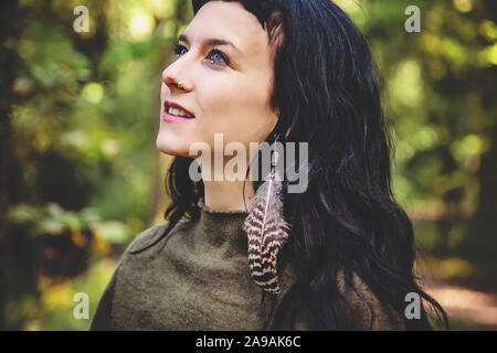 Portrait de belle jeune femme avec feather earring in forest Banque D'Images