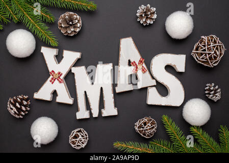 Lettres de noël entouré de branches d'arbres de Noël, des boules et cônes de décorations. Vue supérieure de la composition, de mise à plat. Banque D'Images