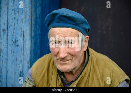 Portrait d'un homme âgé dans un béret sur le porche d'une maison de village Banque D'Images