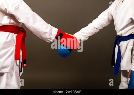 Deux petites filles en kimonos de karaté et plein de musique en rouge et bleu se serrent la main avant la compétition Banque D'Images