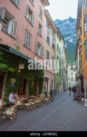 Un couple s'asseoir dans une zone piétonne tranquille, bénéficiant d'une 'All'aperto' apéritif : Via Santa Maria, Riva del Garda, Trentino, en Italie Banque D'Images