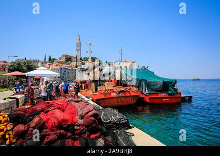28.06.2019, Rovinj, Istrie, Croatie - Les pêcheurs réparer les filets de pêche dans le port de pêche de la ville portuaire de Rovinj, derrière la vieille ville avec l'église Banque D'Images