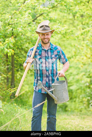 Les plantes en croissance. Chapeau de cow-boy homme mûr avec arrosoir et pelle. Jour de l'arbre. La plantation d'arbres. L'engagement et des responsabilités. Concept de l'agriculture. La plantation dans le jardin. La plantation de la tradition. Banque D'Images