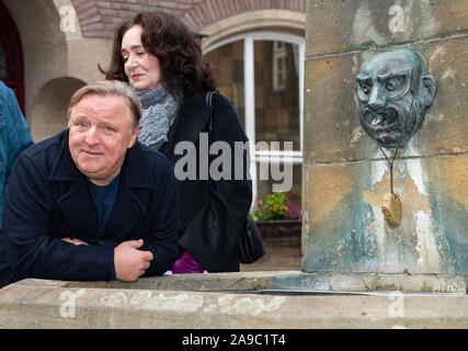 14 novembre 2019, en Rhénanie du Nord-Westphalie, Münster : l'acteur Axel Prahl (l) s'appuie contre la fontaine en face de la Kiepenkerl, l'emplacement de la nouvelle scène de crime "limbe" à Münster. L'actrice Mechtild Grossmann se tient dans le dos. Photo : Guido Kirchner/dpa Banque D'Images