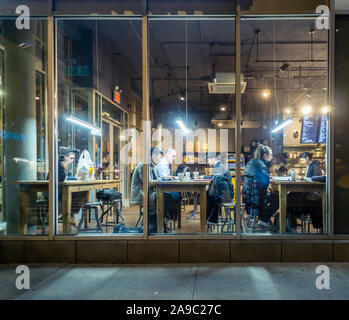 Les clients travailler et profiter de la connexion Wi-Fi gratuite dans un café à Chelsea à New York le Mardi, Novembre 12, 2019. Le wi-fi et les tables communes encouragent l'utilisation de la cafétéria comme un espace de co-working. (© Richard B. Levine) Banque D'Images