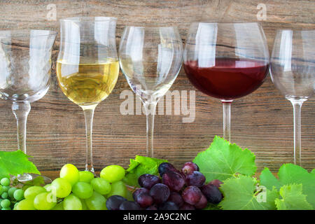 Vin rouge et blanc avec des raisins contre fond de bois Banque D'Images