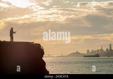 Silhouette d'un pêcheur, avec la ville de San Francisco en arrière-plan, Californie, Etats-Unis, le matin. Banque D'Images