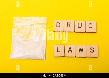 La justice ou la criminalité concept montrant un paquet de médicaments sur un fond jaune avec des menottes, un écriteau lois sur les drogues Banque D'Images