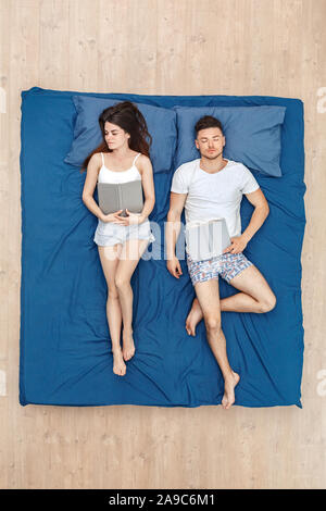 L'heure du coucher. Couple avec des livres sur la vue de dessus de lit Banque D'Images