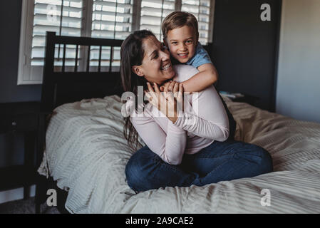 Smiling 5 yr old boy hugging heureuse maman dans la chambre près de window Banque D'Images