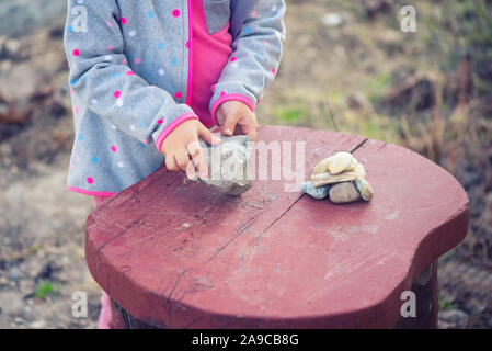 Enfant jouant avec des pierres sur une table rouge Banque D'Images