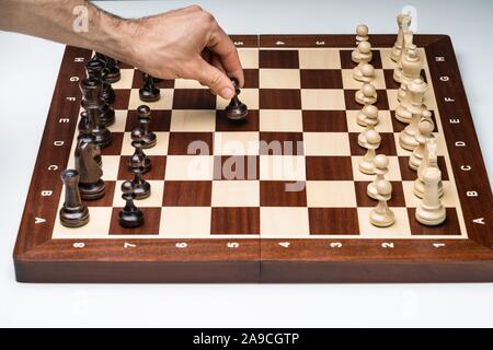 Une vue de dessus de la main de l'homme jouant le jeu d'échecs sur fond blanc Banque D'Images