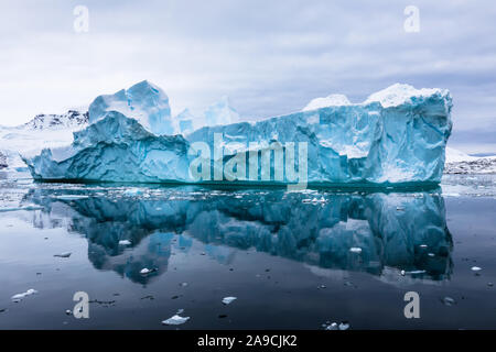 Iceberg impressionnant avec glace bleue et belle réflexion sur l'eau dans l'Antarctique, paysage pittoresque en Péninsule Antarctique Banque D'Images