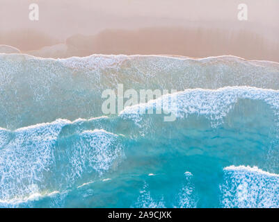 Plage de l'océan vue aérienne de haut en bas avec de l'eau bleue, les vagues d'écume et de pulvérisation et de sable fin, belle destination vacances vacances d'été Banque D'Images