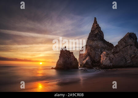 Coucher du soleil à Ursa plage, dans la côte ouest du Portugal, près de Sintra. Des formations de roche de l'aiguille, une longue exposition des vagues sur le sable. Praia da Ursa. Banque D'Images