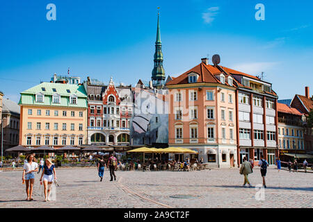 Belle vue sur la vieille ville médiévale de Riga, vue autour de la place de la cathédrale à l'église Saint Pierre, les touristes et les filles lettones Banque D'Images