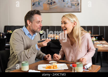 Couple, smiling, manger des sushis, de la moitié, portrait Banque D'Images