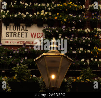 Plaque de rue de la rue de Floral City of westminster WC2, Londres, Angleterre, RU est vu dans entre un affichage des fleurs et éclairé par une lampe de rue vintage. Banque D'Images