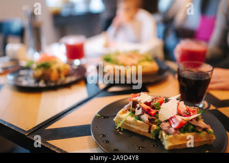 Les gaufres avec du bacon sandwich grillé et salade frech sur plaque noire. Arrière-plan de table en bois Banque D'Images