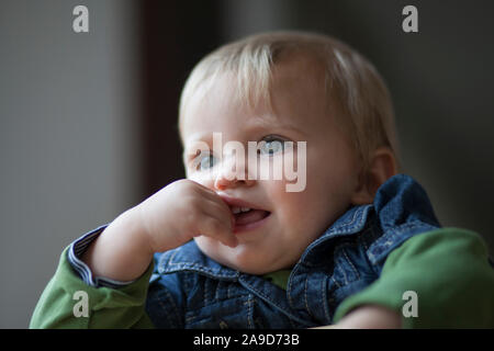 Bébé, fille blonde avec le doigt dans la bouche, la moitié portrait Banque D'Images