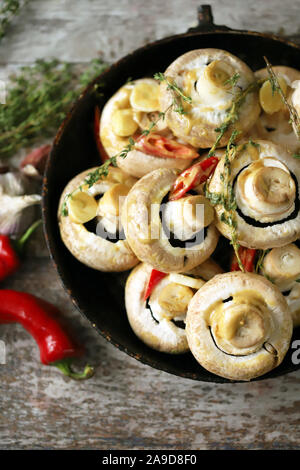 Grands champignons crus dans une casserole. Champignons en sauce avant la cuisson. Cuisine végétalienne. Champagnes crus marinés dans une sauce au thym Banque D'Images